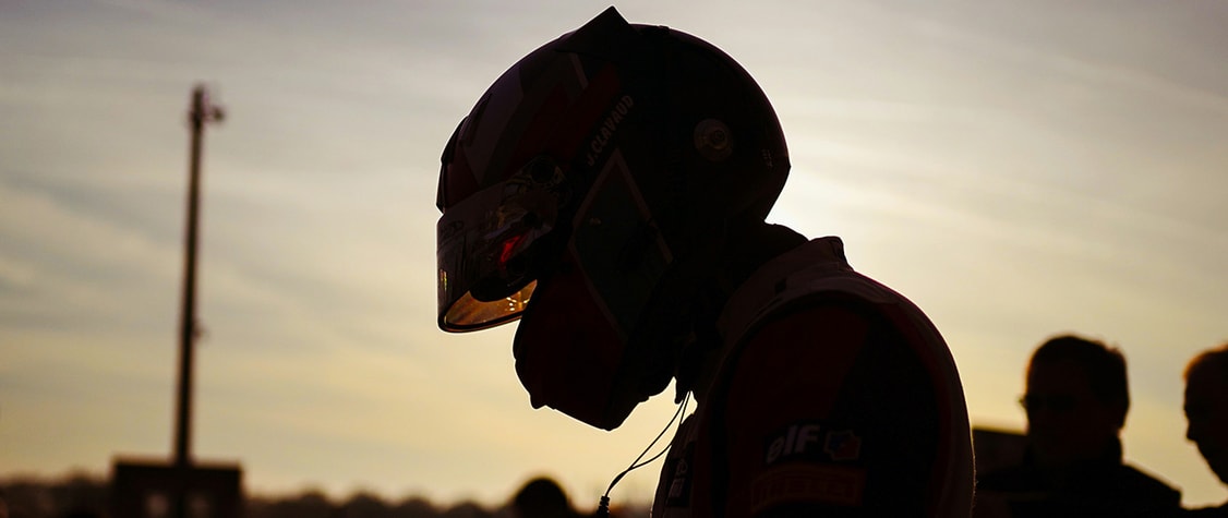 formula one rider helmeted profile against the sun