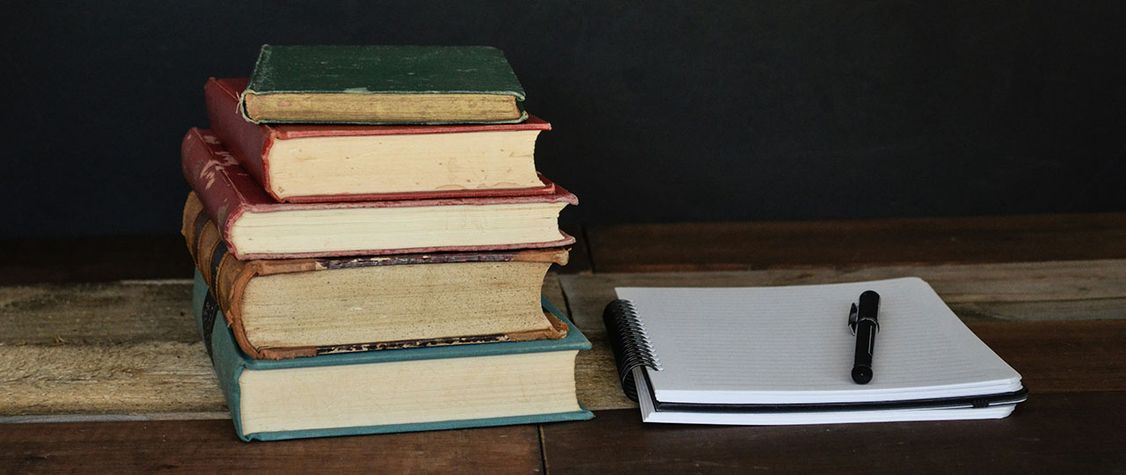 five books next to a notebook
