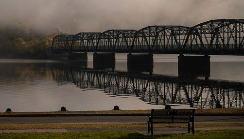 empties-george-zebrowski-excerpt_body_one A bench in front of a river and a bridge