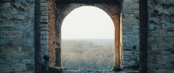 portal-fantasy-like-this-kingdom-will-not-kill-me a window frame of stone overlooking forest hills