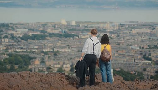 one-day-screenshot a couple looks at a city from a high vantage in the screenshot of the 'one day' trailer