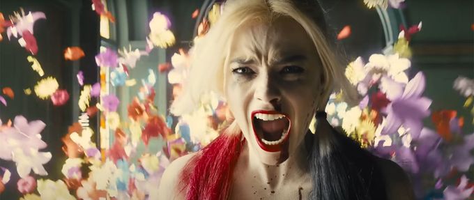 the-suicide-squad screenshot from 2021 suicide squad shows harley quinn screaming with flowers behind