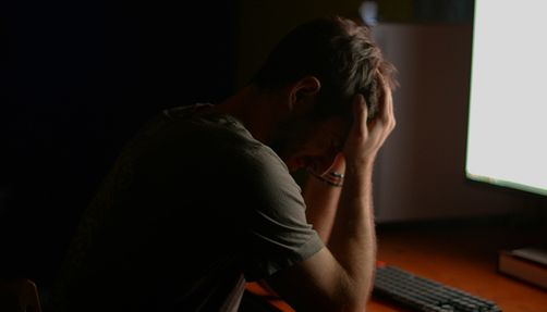 empties-george-zebrowski-excerpt_body_two Man at a desk in front of a computer with his head in his hands.