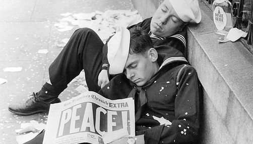 Two sailors asleep with a newspaper declaring "Peace!"